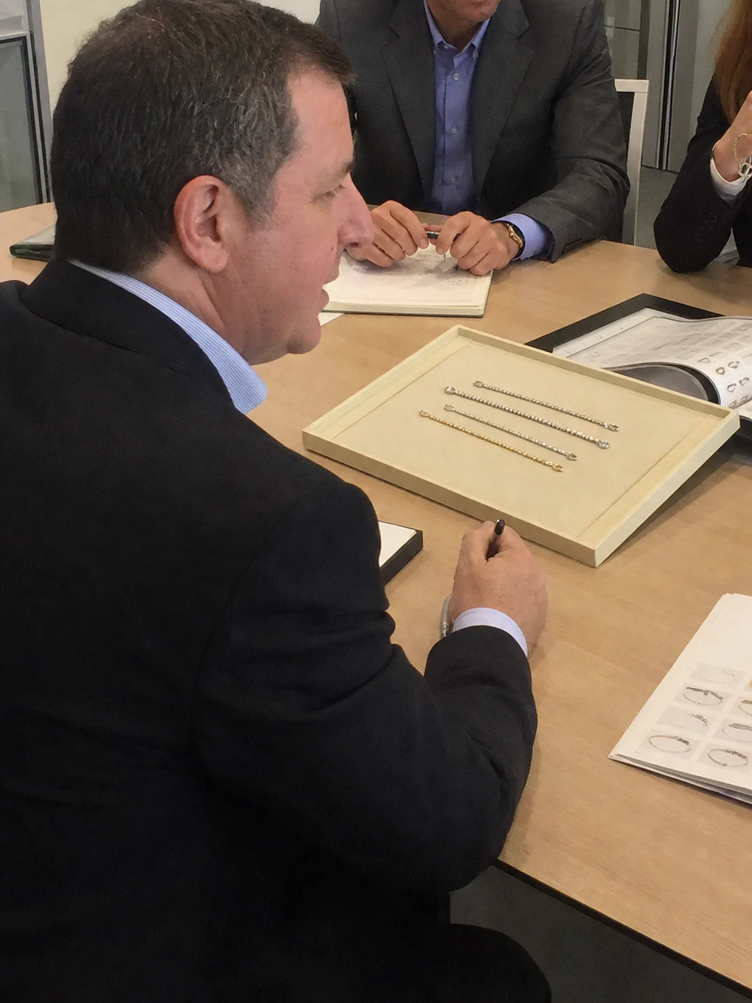 Private jewelry partnership meeting with bracelet samples and product catalogs in 2016.