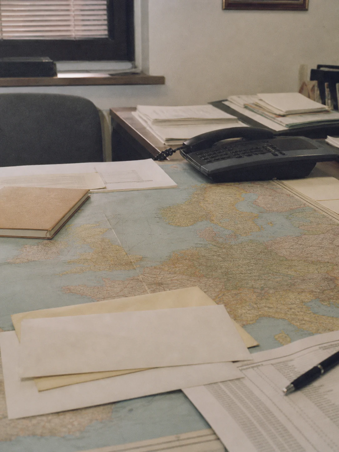 Office desk with a European map, phone, and documents representing SIRO commercial planning in 2004.